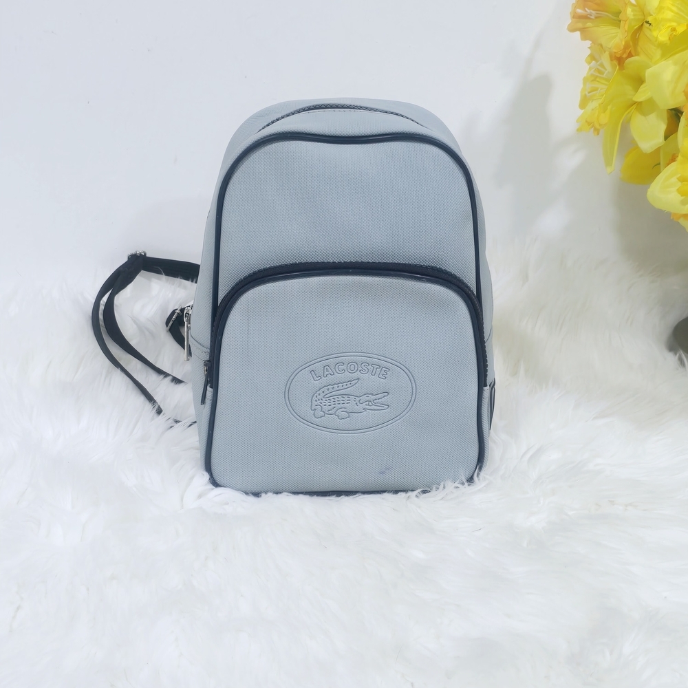 Lacoste mini backpack in a soft light blue shade with navy blue trim accents.